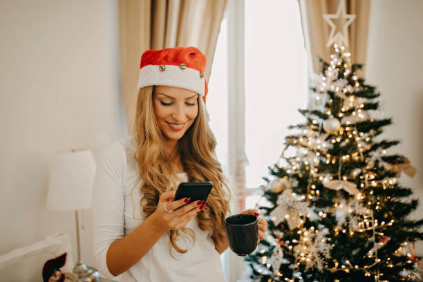 istock Young woman wearing santa hat using cell phone 1283689800
