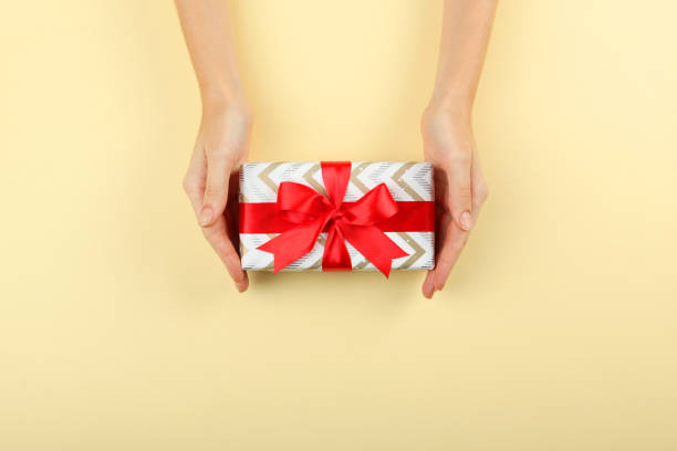 istock gift in female hands on a colored background top view. 1283689963