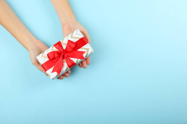 istock gift in female hands on a colored background top view. 1283690032