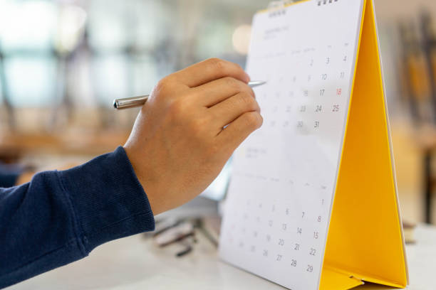 nahaufnahme auf mitarbeiter mann hand mit finger zeigen zeitplan (zeitplan) im kalender zu schreiben liste der arbeit und machen termin-meeting oder verwalten zeitplan jeden tag , life-balance-konzept - august calendar stock-fotos und bilder