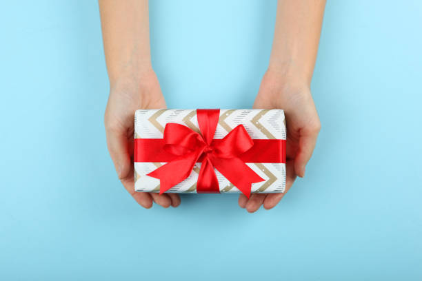 istock gift in female hands on a colored background top view. 1283690731