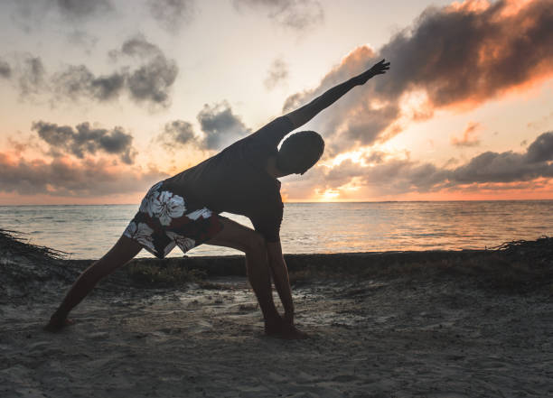 istock Practicing yoga and meditation in summer on beach in sunset 1283690815