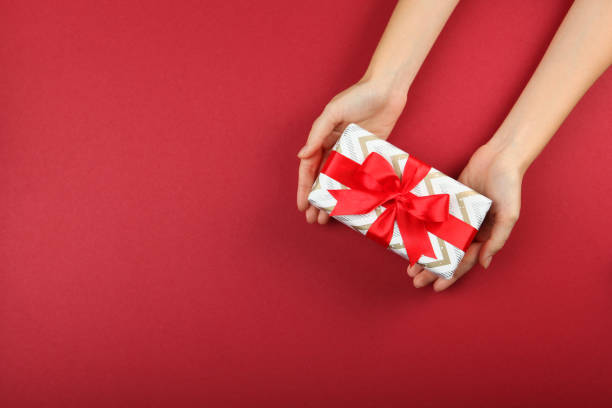 istock gift in female hands on a colored background top view. 1283690903