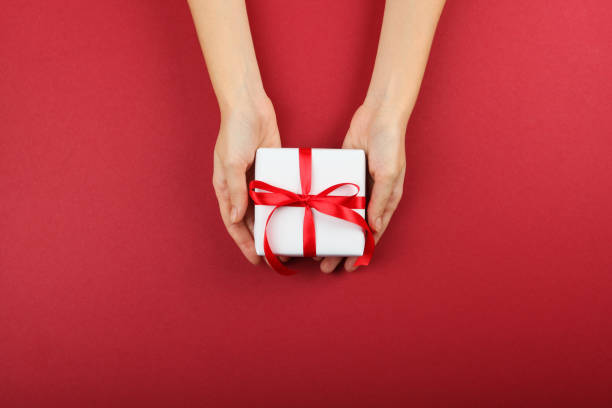 istock gift in female hands on a colored background top view. 1283692127