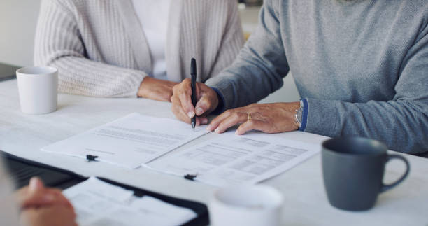 Signing up for a secure future Cropped shot of a senior couple meeting with a consultant to discuss paperwork at home contract stock pictures, royalty-free photos & images