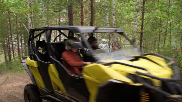 People Driving ATV Uphill in Forest