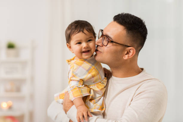 szczęśliwy ojciec całuje córeczkę w domu - father fathers day baby child zdjęcia i obrazy z banku zdjęć