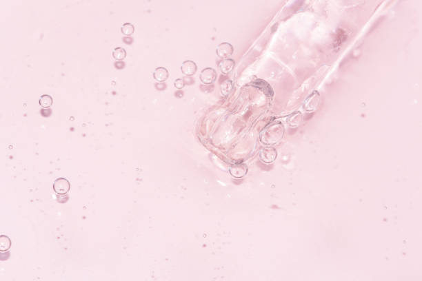 detail of a pipette with pouring serum and droplet with shadow detail of a pipette with pouring serum and droplet with shadow on a pink background blood serum photos stock pictures, royalty-free photos & images