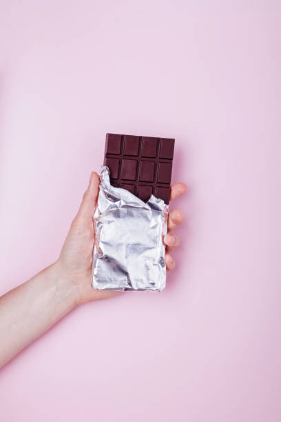 istock Hand holds dark chocolate bar in foil. 1283695107