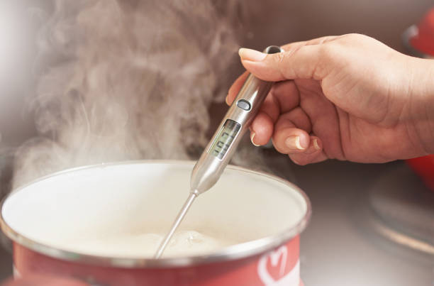 Female hand measures the temperature in the pan with an electronic cooking thermometer stock photo
