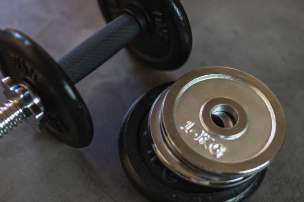 istock Dumbbell with stacked iron weight plates of different weights and sizes on a concrete surface 1283696315
