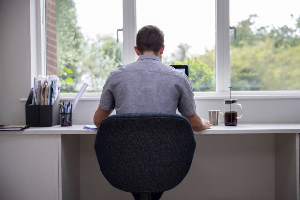 istock Rear View Of Man Working From Home On Computer  In Home Office 1283696323
