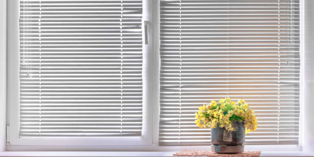 istock window with white blinds and flower pot on windowsill at home 1283696486