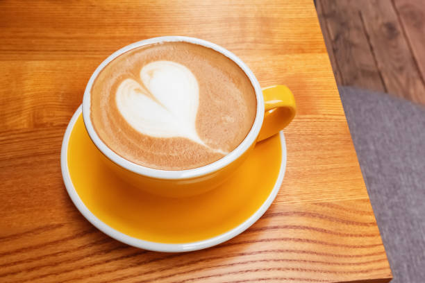 istock Yellow cup of coffee with heart shaped latte art 1283696528