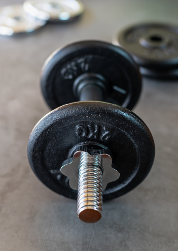 Dumbbell with 2 kg iron plates on a concrete surface and with more weight plates at the bottom