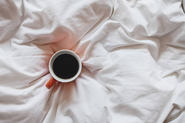 istock Cup of coffee on bed, top view 1283697783
