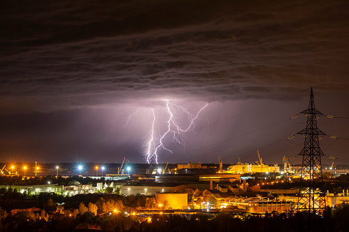 Dramatic stormy clouds at night with distant lightning behind the city lights near Monfalcone (Italy) on 20 august, 2017.