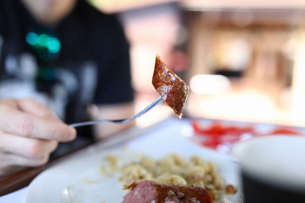 Man on fork holds piece of fatty sausage. Menu for coffee and restaurants concept