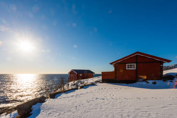 istock Sun flare on renovated traditional red rorbu fishing hut with empty racks for drying cod on the Lofoten islands in Norway in winter on the coast 1283700714
