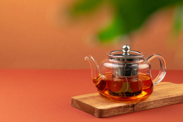 istock Glass teapot with black tea on background of blurred foliage 1283700953