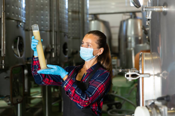 istock Female winemaker in protective mask analyze the white wine in beaker 1283701012