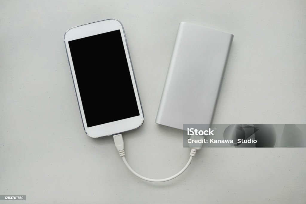 Power Banks for Charging Up Your Phone on the Go High angle view shot of a smartphone getting charged using a power bank. Power Bank Stock Photo