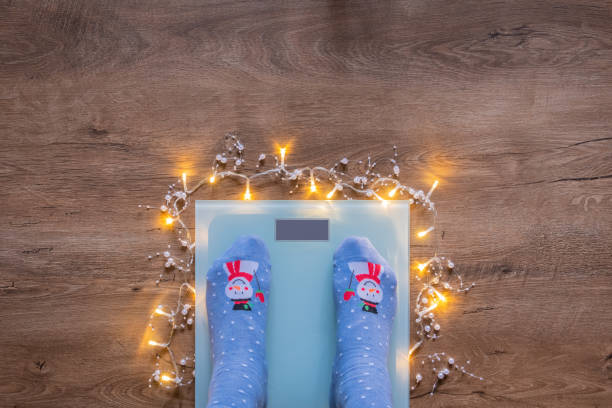 Woman legs in Christmas socks on scales on wooden floor stock photo