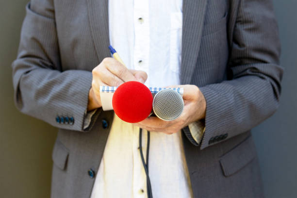 istock Correspondent or reporter at media event, holding microphone, writing notes. Journalism concept. 1283703216