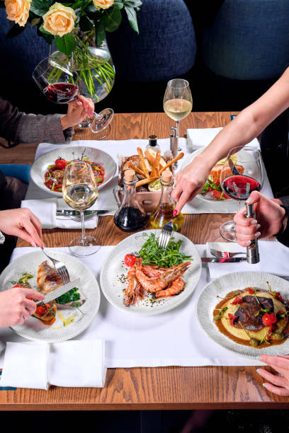 istock Hands of four people at a table with food. 1283704282