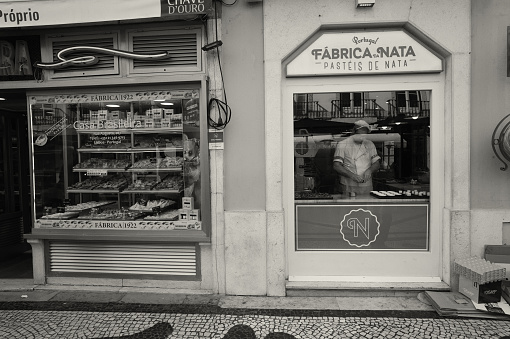 Lisbon, POrtugal - February 11, 2020: A cook works by a shop window in the Rua Augusta street in Lisbon downtown.