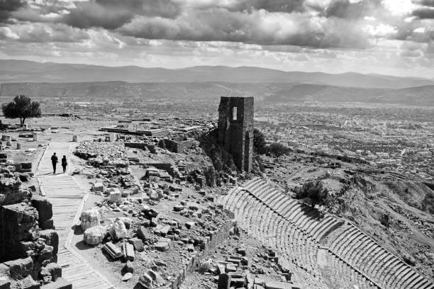 Bergama/İzmir 10/14/2020 The ancient city was taken from above. Amphitheater. The walking path is the couple walking on the tree path at the end of this path. Background has Bergama city and mountains. It was taken at noon in a covered air.Pergamon is the name of the ancient city in place of Bergama old building houses in İzmir province today. Pergamon was one of the important centers of Misya in ancient times. It was the capital of the Kingdom of Pergamon between 282-133 BC.
