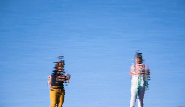 istock Reflection of two people  in a lake water 1283708686