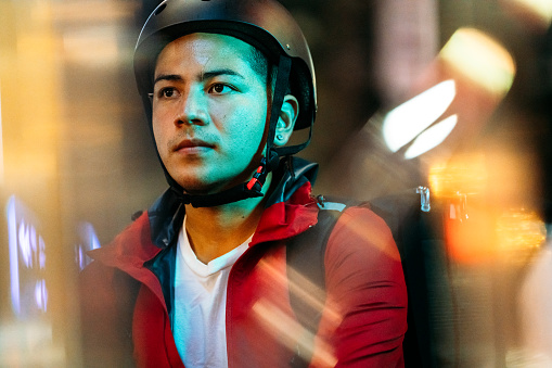 A portrait of a food delivery person at a rainy night.