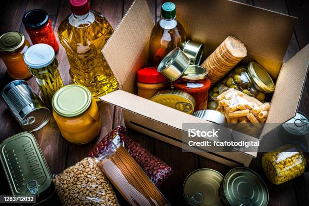 Cardboard Box Filled With Nonperishable Foods On Wooden Table High Angle View Stock Photo - Download Image Now