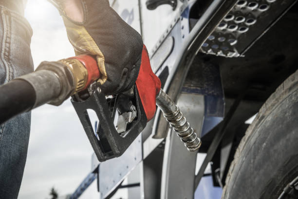 Truck Driver Hold Fuel Pump Nozzle in His Hand Truck Driver Wearing Safety Gloves Holding Fuel Pump Nozzle in His Hand and Performing Vehicle Refueling. Transportation and Automotive. refueling stock pictures, royalty-free photos & images