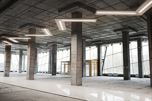 Background image of empty building under construction with concrete columns and graphic ceiling lamps, copy space