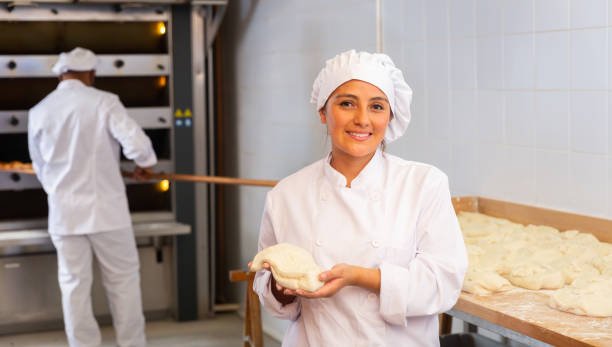 istock Woman baker smiling at camera during daily work with dough 1283713979