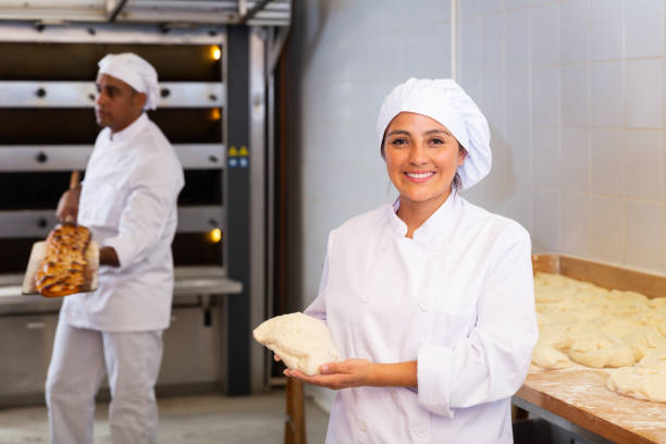 istock Woman baker smiling at camera during daily work with dough 1283713983