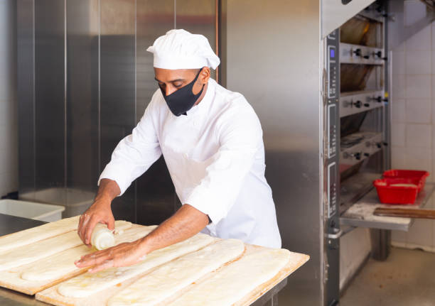 istock Baker preparing raw cocas for baking, pouring olive oil 1283713993