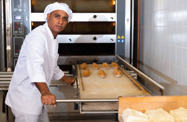 istock Male bakery worker pulls bread pan out of oven 1283714020