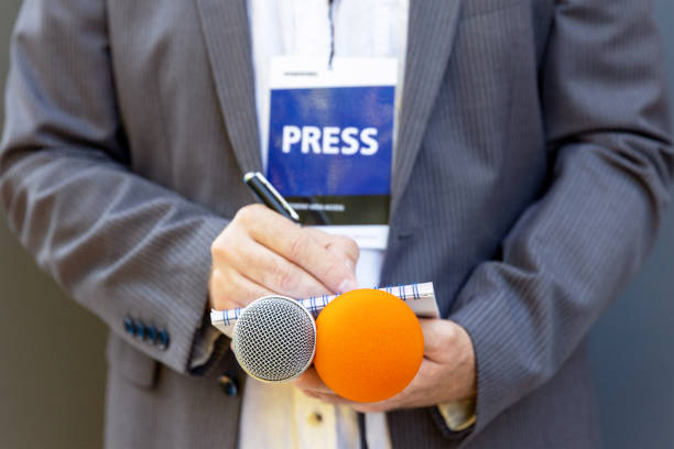 istock Correspondent or journalist at media event, holding microphone, writing notes. Journalism concept. 1283714106