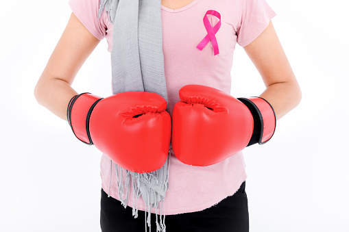 Muslim religious women in hijab put a pink ribbon on their tops. And wearing boxing gloves on a colored background. Breast cancer concept, cancer prevention concept.