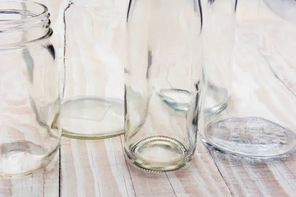 An abstract closeup of empty glass bottles on a rustic wooden table.