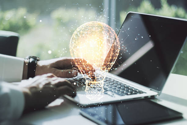 Double exposure of creative light bulb hologram with hands typing on laptop on background, research and development concept