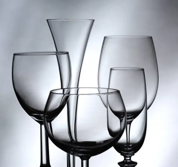 Five wine and champagne glasses against a gray mottled background. Square Format.