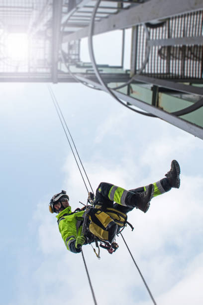 istock Manual rope access technician - worker abseil from tower - antenna in sunshine 1283723815