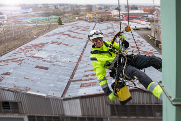 istock Manual rope access technician - worker abseil from tower - antenna and smiling, in sunshine and town behind 1283723843
