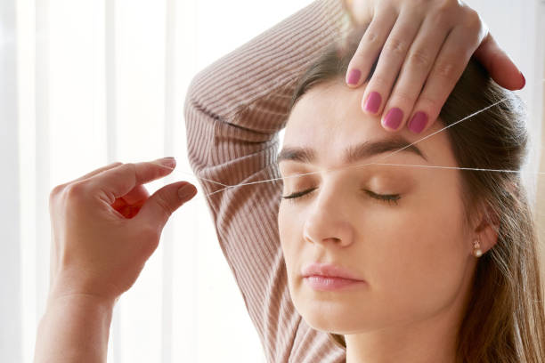 istock Cosmetologist plucks client eyebrows by thread in the beauty salon 1283727030