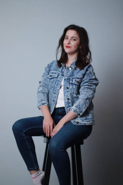 istock attractive brunette in jeans and denim jacket on grey background. studio shoot 1283729147