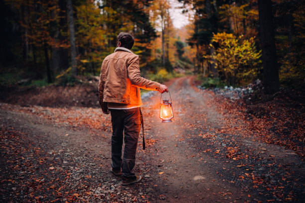 A man with a lantern at a crossroads in the woods